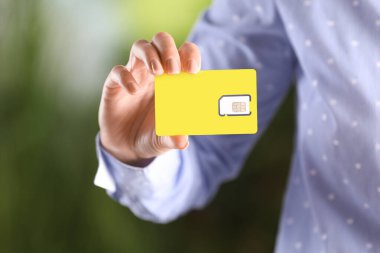 Bulanık arkaplanda SIM kartı tutan kadın, yakın plan