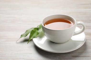 Yeşil çayı fincanda tazeliyor ve yaprakları gri ahşap masada, yakın plan. Metin için boşluk