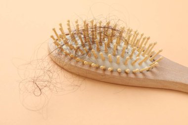 Bej arka planda saçı dökülmüş bir fırça, yakın plan. Alopecia sorunu