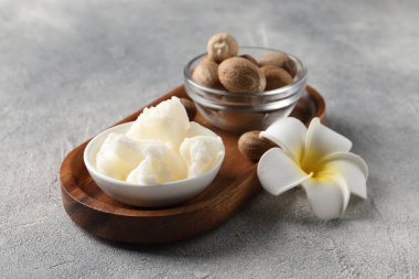 Kasede doğal Shea yağı, fındık ve gri masadaki plumeria çiçeği.