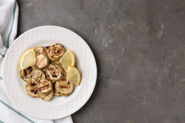 Lezzetli ızgara kabak dilimleri, gri desenli masada limon, üst manzara. Metin için boşluk