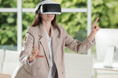 Ofiste sanal gerçeklik kulaklığı kullanan gülümseyen kadın.