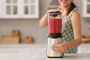 Mutfaktaki beyaz mermer masada blender ile nefis smoothie yapan kadın, yakın plan. Metin için boşluk