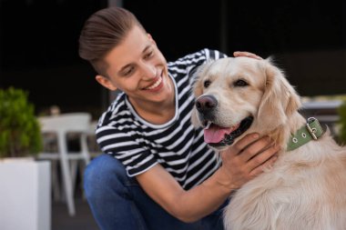Mutlu sahibi dışarıda sevimli Golden Retriever köpeğini okşuyor.
