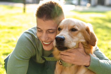 Güneşli bir günde sevimli köpeğiyle parkta genç bir adam.
