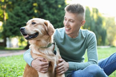 Parkta sevimli köpeğiyle genç bir adam.