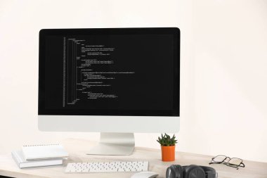 Programcının işyeri. Tamamlanmamış kodu, kulaklığı ve malzemesi olan modern bilgisayar.