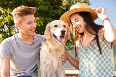 Güneşli bir günde dışarıda sevimli Golden Retriever köpeği olan mutlu çift.