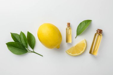 Beyaz arka planda gerekli yağlar, limon ve yeşil yapraklar.