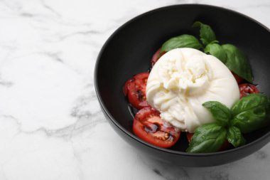 Lezzetli burrata peyniri, domates ve fesleğen beyaz mermer masada, yakın plan. Metin için boşluk