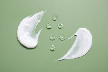 Face cream and gel on green background, top view clipart