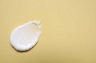 Soluk sarı arka planda yüz kremi, üst manzara. Metin için boşluk