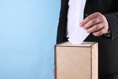 Adam oyunu açık mavi arka plana karşı sandığa koyuyor, yakın plan. Metin için boşluk