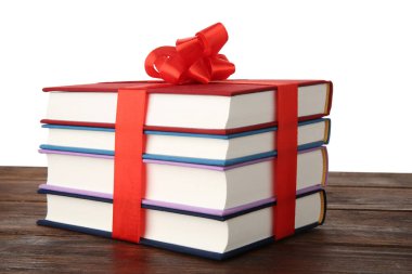 Beyaz arka plana karşı ahşap masada kurdeleli kitap yığını