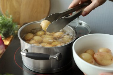 Ocağa patates koyan kadın, yakın plan.