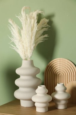 Güzel dekoratif bitkiler, vazolar ve ahşap tahtalar kapalı yeşil duvarın yanındaki masada.