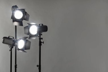 Gri fotoğraf arkaplanı ve profesyonel ışıklandırma ekipmanları stüdyoda. Metin için boşluk