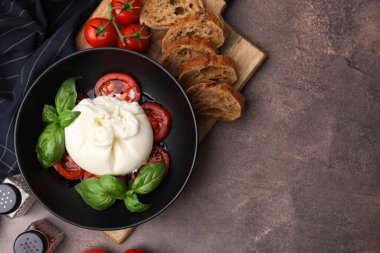 Lezzetli burrata peyniri, domates, fesleğen ve ekmek kahverengi masada, düz yerde. Metin için boşluk