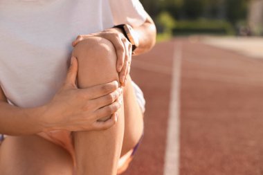 Stadyumda dizinden yaralanan sporcu kadın, yakın plan. Metin için boşluk