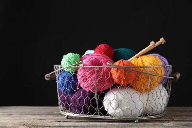 Bir sürü yumuşak iplik ve örgü iğneleri ahşap masada metal sepetin içinde.