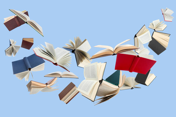 Many different books in air on light blue background