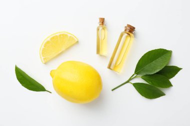Beyaz arka planda gerekli yağlar, limon ve yeşil yapraklar.