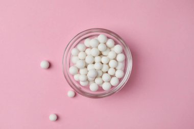 Homeopatik tedavi. Pembe arka planda cam kasede haplar, üst manzara.