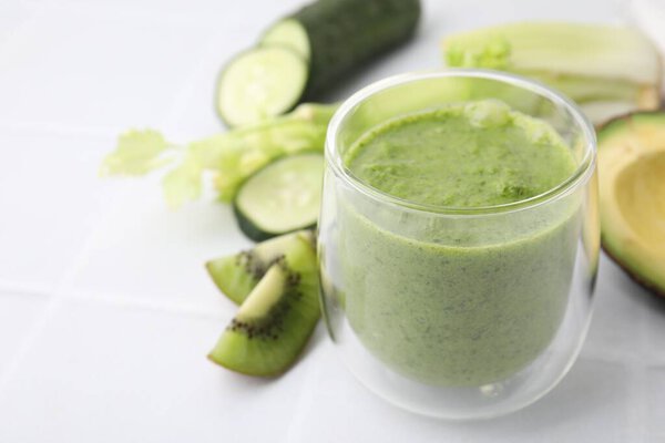 Delicious green smoothie and ingredients on white table, closeup. Space for text