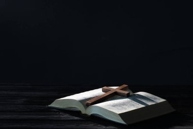 İncil ve haç siyah ahşap masa üzerinde karşı karanlık arka plan, metin için boşluk. Hıristiyanlık Dini
