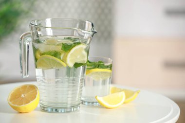 Sürahi içinde nane ve beyaz masada cam ile limonata tazeleniyor. Metin için boşluk