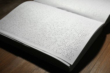 Tahta masanın üzerinde Braille metni olan bir kitap, yakın plan. Körler için eğitim ve eğlence