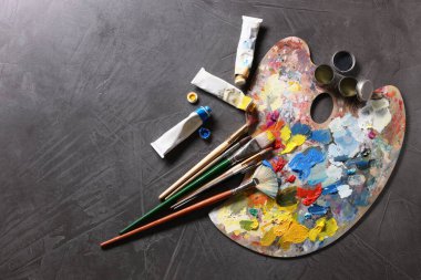 Sanatçı paleti, fırçalar ve boyalar gri masada, düz yerde. Metin için boşluk