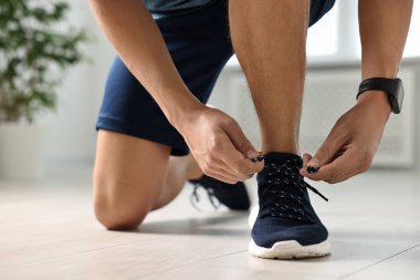Spor ayakkabısının bağcığını bağlayan adam, yakın plan.