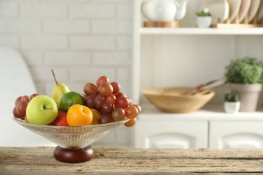 Ahşap masada farklı taze meyveler bulunan cam vazo. Metin için boşluk