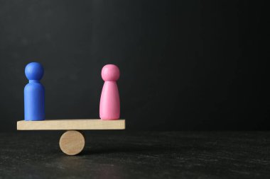 Cinsiyet eşitliği kavramı. Gri arkaplan ve metin için alan karşılaştırması yapan erkek ve kadın figürler
