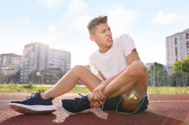 Spor sakatlığı. Stadyumda bacak ağrısı çeken bir adam.