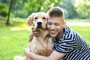 Parkta sevimli köpeğiyle genç bir adam.