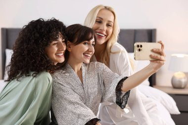 Mutlu arkadaşlar yatak odasında selfie çekiyor. Spa partisi