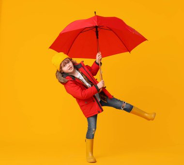 Turuncu arka planda kırmızı şemsiyeli küçük çocuk