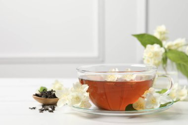 Bardakta sıcak yasemin çayı ve beyaz mermer masada çiçekler, metin için yer