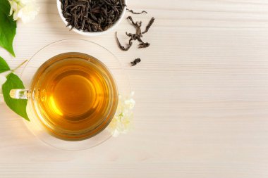 Sıcak yasemin çayı fincanda ve çiçekler beyaz ahşap masada, düz yerde. Metin için boşluk