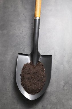 Gri masa üzerinde toprak olan metal kürek, üst manzara.