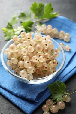 Kasede taze kuşüzümü ve gri desenli masada yeşil yapraklar, yakın plan.