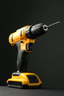 Gri masa üzerinde modern kablosuz elektrik matkabı siyah arkaplana karşı