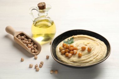 Beyaz ahşap masada zeytinyağı, nohut ve maydanozlu lezzetli humus.