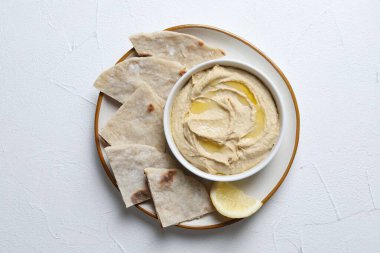 Kavanozda zeytinyağı ve açık dokulu masa üzerinde pide ile nefis bir humus.