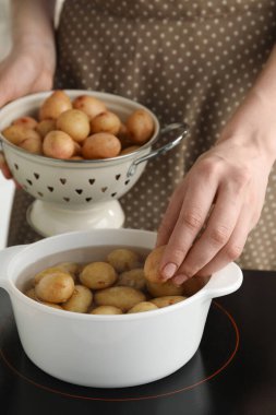 Ocakta patatesi tencereye koyan kadın, yakın plan.