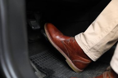 Man pushing on pedal of car brake, closeup clipart