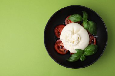 Lezzetli burrata peyniri, domates ve fesleğen yeşil masada, üst tarafta. Metin için boşluk