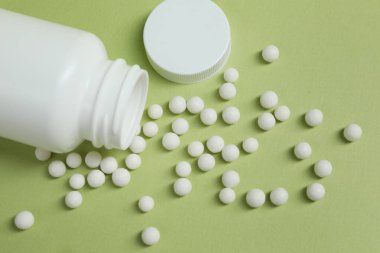 Açık yeşil arka planda Homeopatik ilaç ve şişe